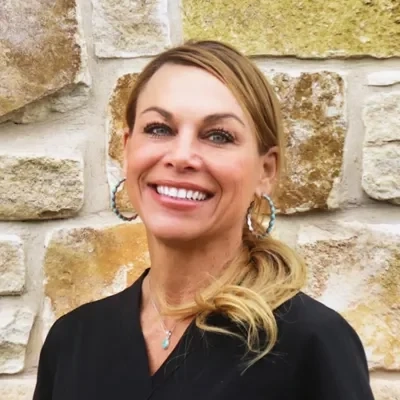 Nurse Provider Sara Williamson smiling in front of a stone wall.